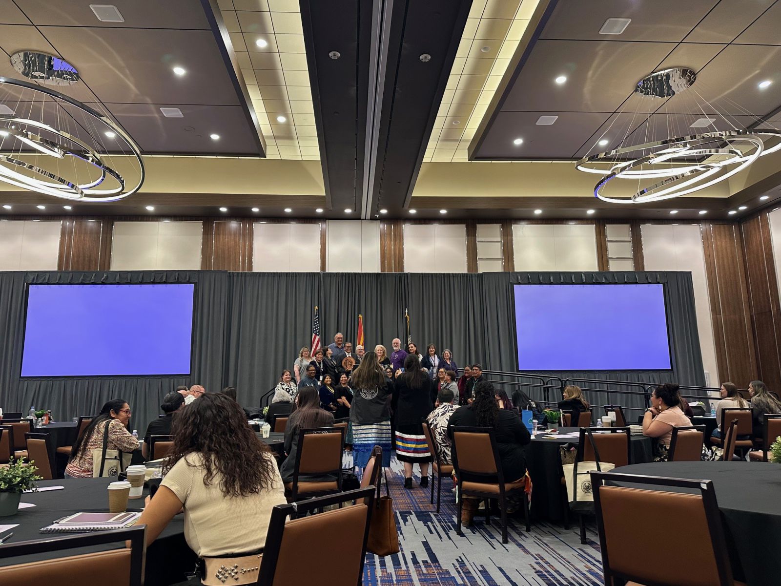 Group standing for photo on stage with flags.